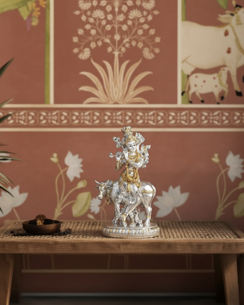 Silver and gold statue of Lord krishna with cow on a table with minimal cow wallpaper in a house 